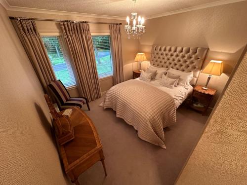 a bedroom with a bed and a chair and a chandelier at One Dunbar Court Gleneagles Village in Auchterarder