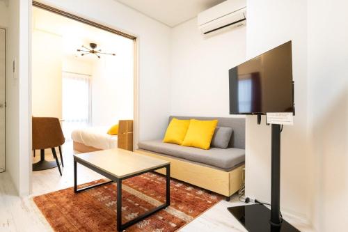 a living room with a couch and a flat screen tv at TASUKI smart Higashishinjuku in Tokyo