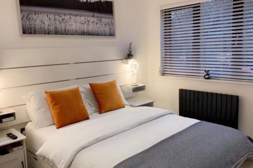 ein Schlafzimmer mit einem Bett mit orangefarbenen Kissen und einem Fenster in der Unterkunft One bedroom posh and neat flat in Thamesmead