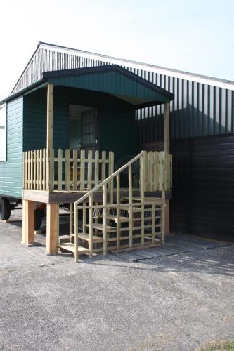 a small green building with a porch and a ramp at Boerenchalet Dirk, Minicamping de Grutte Earen in Burum