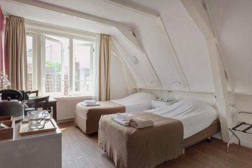 a hotel room with two beds and a window at Hotel Prinsenhof Amsterdam in Amsterdam