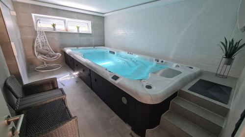 a large bath tub in a bathroom with a chair at Schlaffass mit Wellness in alter Scheune in Seinsheim