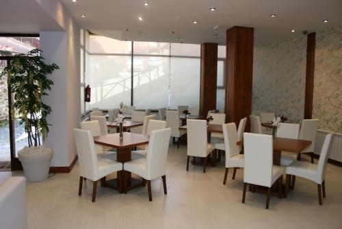 un comedor con sillas y mesas blancas en un restaurante en Hotel Arha Potes & Spa, en Potes