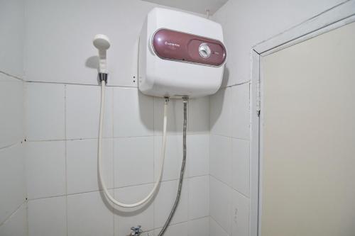 a shower in a bathroom with a soap dispenser on the wall at Room Rendi @ Apt Dramaga Tower in Bogor