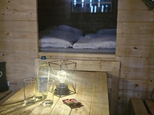 a bottle of water and glasses on a table with a bed at Schlaffass mit Wellness in alter Scheune in Seinsheim