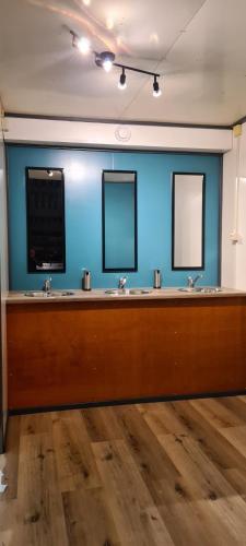 a bathroom with three sinks and two mirrors at Boerenchalet Dirk, Minicamping de Grutte Earen in Burum