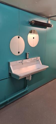 La salle de bains est pourvue d'un lavabo blanc et de deux miroirs. dans l'établissement Boerenchalet Dirk, Minicamping de Grutte Earen, à Burum
