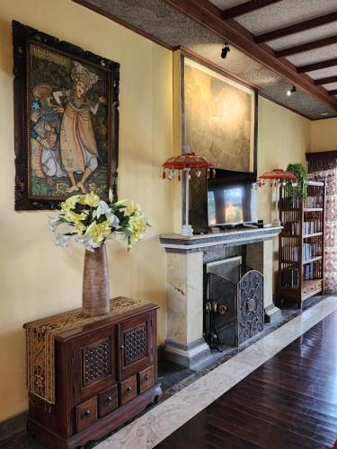 a living room with a fireplace and a painting on the wall at Balinese Villa in Berastagi in Berastagi