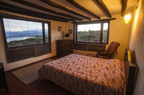 a bedroom with a bed and two large windows at Villa de Leyva da Cecy in Villa de Leyva