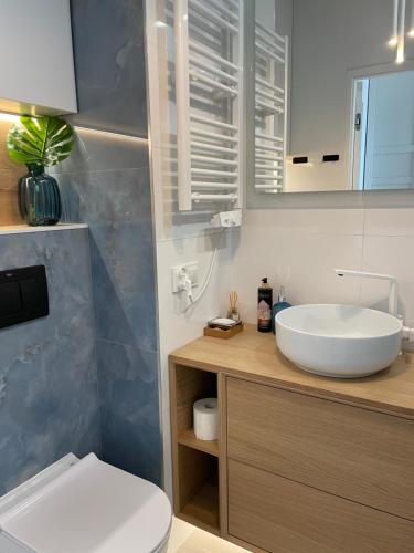 ein Badezimmer mit einem weißen Waschbecken und einem WC in der Unterkunft LeHome Airport Wroclaw in Breslau