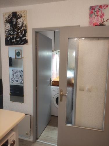 una cucina con porta aperta su un bagno con lavandino di Résidence les caraïbes Cap d'agde - Centre Port- Parking Gratuit-Terrasse - wifi 5G a Cap d'Agde