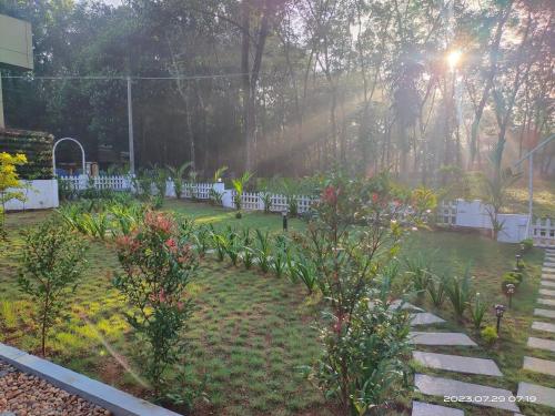 a garden with white chairs and flowers and trees at Merlys Fruit Garden - Resort at Thattekkad in Kotamangalam