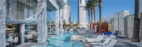 a hotel swimming pool with chairs and palm trees at Huge Modern Luxury 17 Floor Panoramic Corner Suite with OPEN BALCONY in Las Vegas
