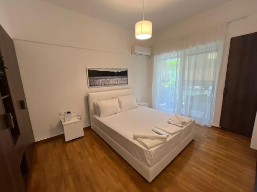 een slaapkamer met een wit bed en een groot raam bij Spacious 2bdr apartment @ Pagrati in Athene