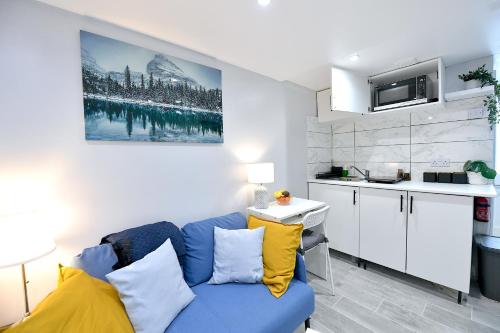 a living room with a blue couch and a kitchen at Cozy Studio retreat in Vibrant Crystal Palace, in Upper Norwood