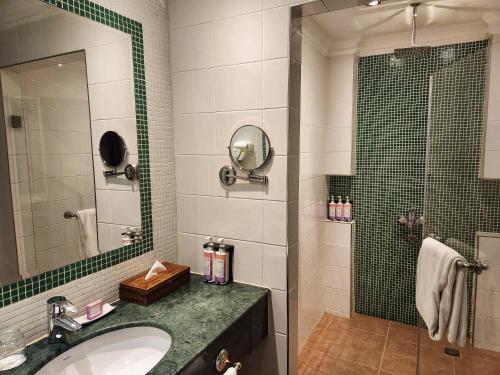 a bathroom with a sink and a shower with a mirror at Montrose - A Mayfair Collection Hotel in Kuwait