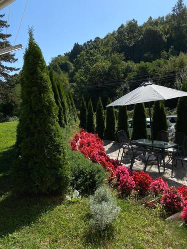 una mesa con sombrilla en un jardín con flores en Zeleni Dvor en Ribarska Banja