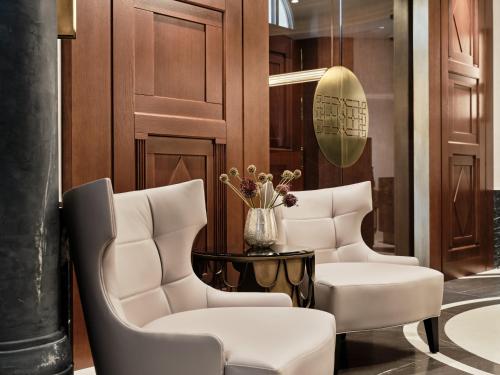 a room with two white chairs and a table at The Crown Krakow Center - Handwritten Collection ACCOR in Kraków