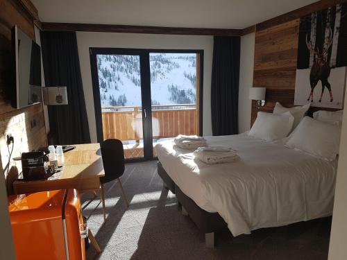 Cette chambre comprend un lit, un bureau et une fenêtre. dans l'établissement Chalet Marano Restaurant & Spa, à Isola 2000