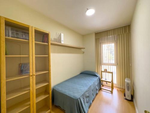 ein Schlafzimmer mit einem Bett, Regalen und einem Fenster in der Unterkunft Apartamento Puerta del Mar in Cádiz