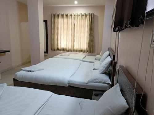 a room with three beds and a window at Hotel Satyam in Jaigaon