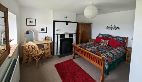 a bedroom with a bed and a desk and a fireplace at Teach Róisin-Traditional Irish holiday cottage in Malin Head. in Malin