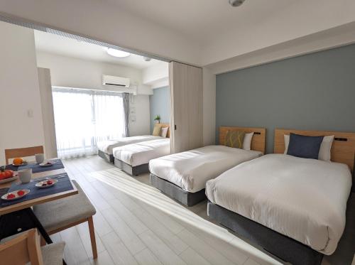 a hotel room with two beds and a table at ESLEAD HOTEL Namba Daikokucho in Osaka