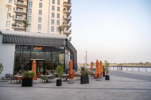a restaurant with tables and umbrellas in front of a building at Yas Escape - Stylish Boho Studio with Pool, Near Yas Mall in Abu Dhabi