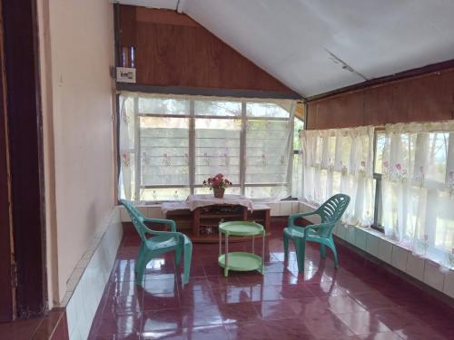 a room with chairs and a table and windows at G - RIMA GARDEN HomeStay in Lengkoajang