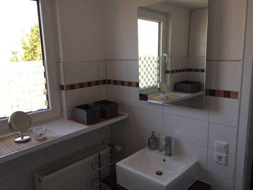 Baño blanco con lavabo y espejo en Ferienwohnung Bergwiese, en Schwarzenbach am Wald