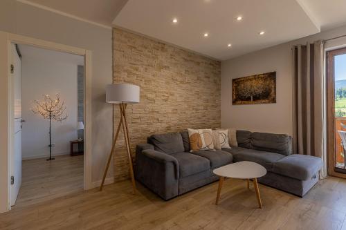 a living room with a couch and a brick wall at RentPlanet - Apartament Bawaria in Szklarska Poręba
