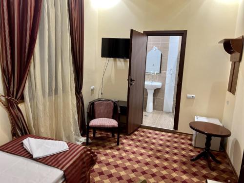 um quarto de hotel com uma cama e uma cadeira e uma casa de banho em Armenian Royal Palace em Yerevan