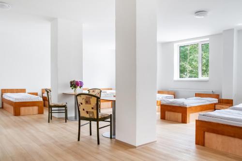 a room with a table and chairs and beds at Hostel Beskydy in Rožnov pod Radhoštěm