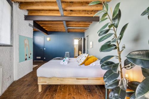 een slaapkamer met een bed met witte lakens en gele kussens bij Industrial loft near the center of Ghent in Gent
