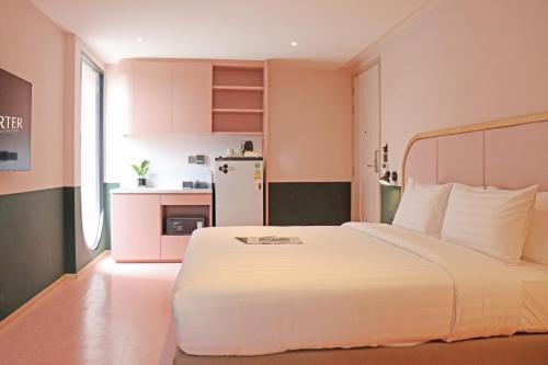 a bedroom with a white bed and a refrigerator at The Quarter Ratchathewi by UHG in Bangkok