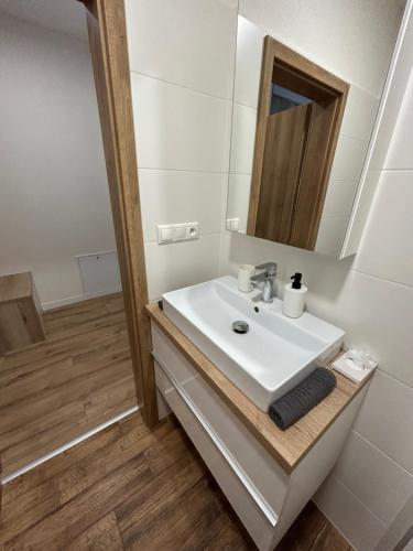 La salle de bains blanche est pourvue d'un lavabo et d'un miroir. dans l'établissement Apartmán Castle Bojnice, à Bojnice