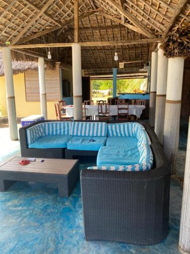 a patio with blue couches and a table and chairs at Mitsio Paradise - Hotel privatif en pension complète in Nosy Mitsio