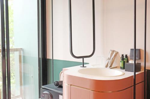 a bathroom with a sink and a mirror on a cabinet at The Quarter Ratchathewi by UHG in Pom Prap