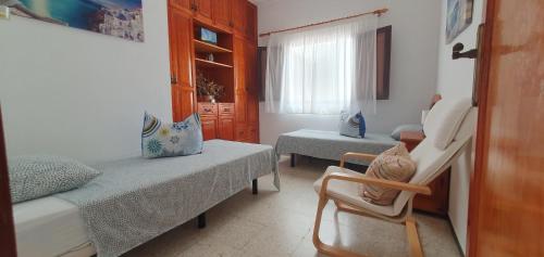 a bedroom with two beds and a chair in it at Casa maria in Puerto del Rosario