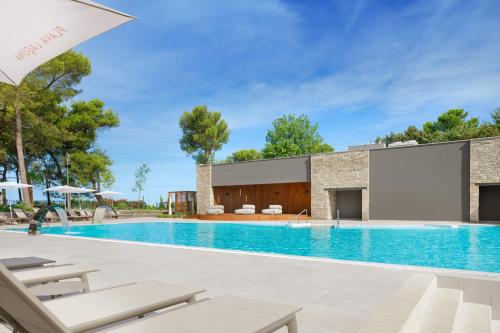 une piscine avec des chaises et un bâtiment dans l'établissement Istrian Villas Plava Laguna, à Umag