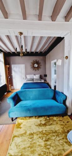 a blue couch in a bedroom with a bed at Chambre d'hôtes Abbatiale in Bernay