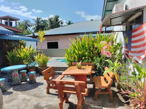 eine Terrasse mit einem Holztisch, Stühlen und Pflanzen in der Unterkunft Sri impiana in Pantai Cenang