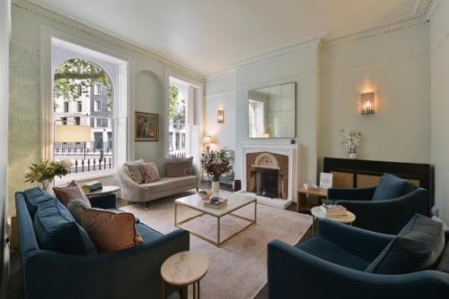 a living room with blue chairs and a fireplace at Harlingford Hotel in London