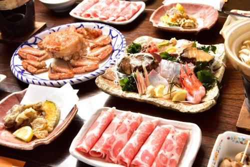 uma mesa coberta com pratos de marisco e outros alimentos em ニャー助のホテルん em Shakotan