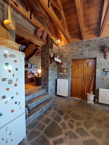 a living room with a refrigerator and a stone wall at Το σπίτι στο χωριό in Kipoi