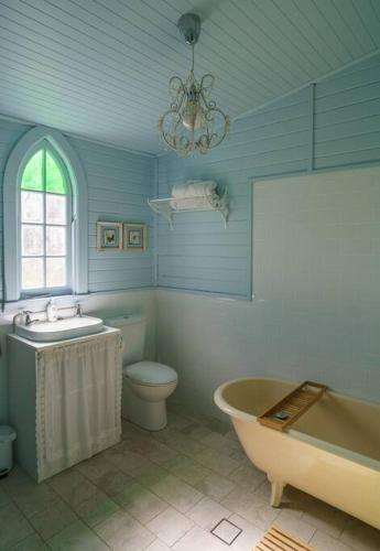 a blue bathroom with a tub and a toilet and a sink at St Aidan's - Converted Church in Mudgee