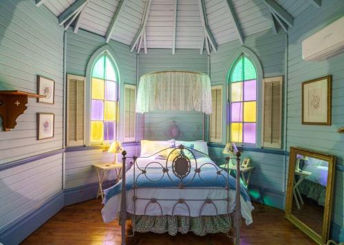 a bedroom with a bed and stained glass windows at St Aidan's - Converted Church in Mudgee