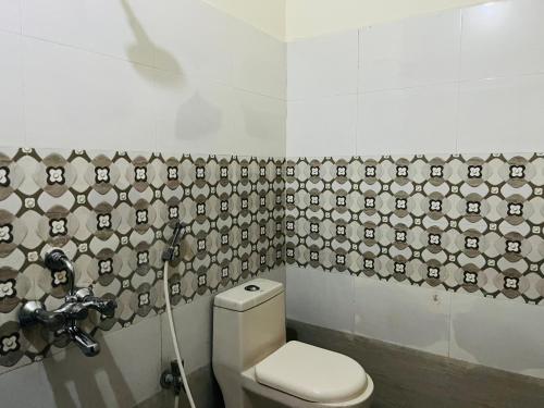 a bathroom with a toilet and a wallpaper with faces on it at Hotel Plaza Hyderabad Airport Zone in Shamshabad