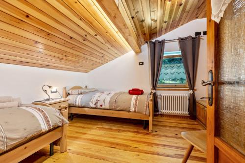 Duas camas num quarto com tectos em madeira em Baita Cisina 
