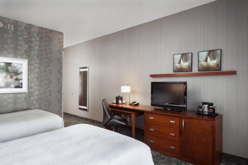 a hotel room with a desk with a television and a bed at Courtyard by Marriott Stockton in Stockton